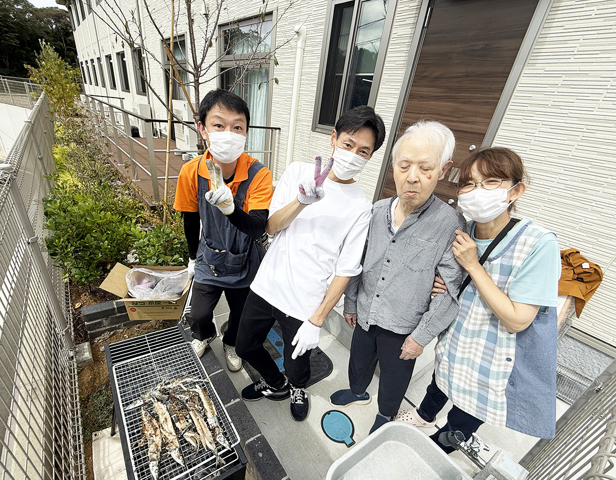 炭火で秋刀魚を焼くヘルパーと記念撮影